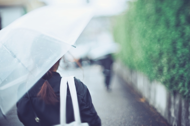 雨の中傘をさして歩く女性